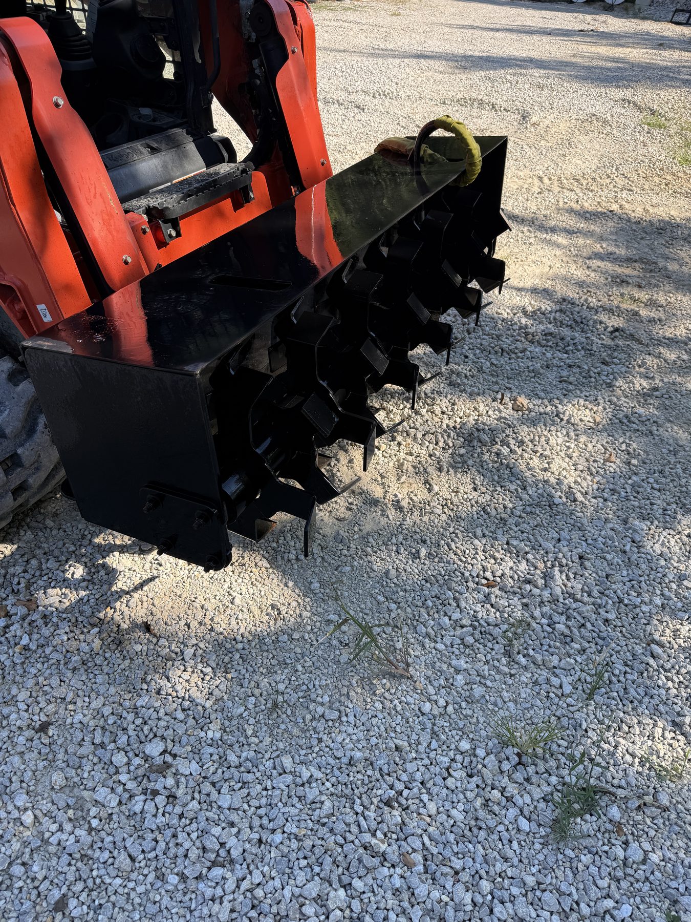 Hydraulic rotary tiller attachment mounted on a compact track loader